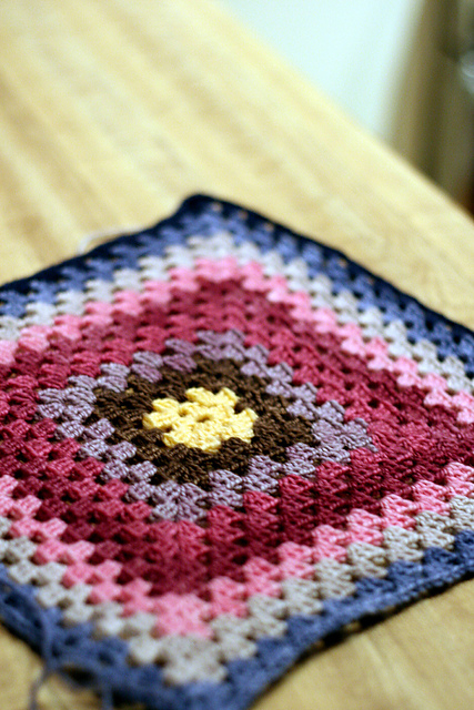 a crocheted granny square blanket in rich jewel tones